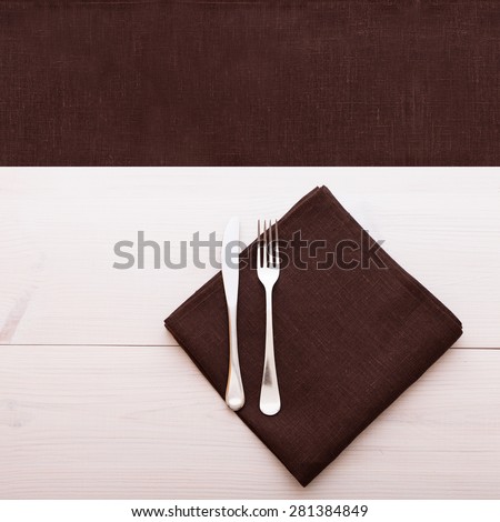 Empty desk and cutlery on table cloth on wooden table for dinner. Flat mock up for design. Top view square.