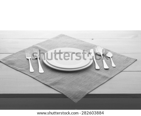 Empty plates and cutlery on table cloth on wooden table for dinner. Top view. Flat mock up for design. Black and White