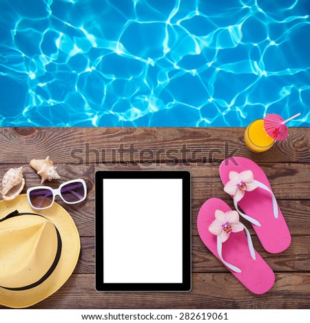Blank empty tablet computer on beach. Trendy summer accessories on wooden background pool. Sunglasses, orange juice and flip-flops on beach. Tropical flower orchid. Flat mock up for design.