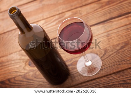 Glass of red wine and bottle on wooden background. Flat mock up for design.