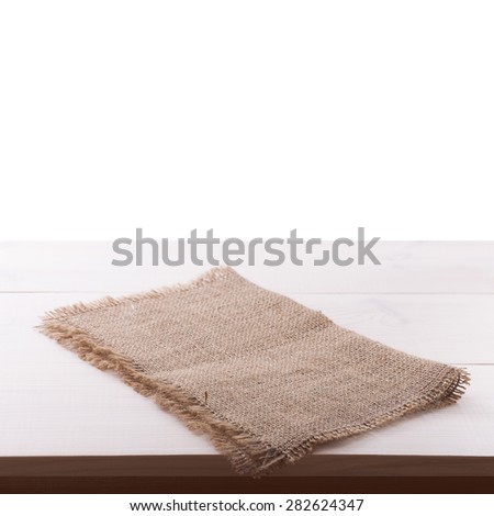 Top view of rough burlap napkin tablecloth on white wooden table isolated. Flat mock up for design.