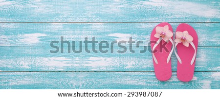 Summer vacation. Pink sandals on blue wooden texture. Beach accessories. Flat mock up for design.