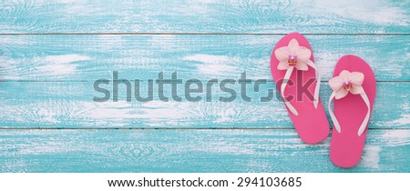 Summer vacation. Pink sandals on blue wooden texture. Beach accessories. Flat mock up for design.