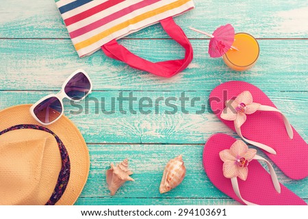 Summer vacation. Pink sandals and beach accessories. Blue wooden texture . Flat mock up for design. Beautifully toned image