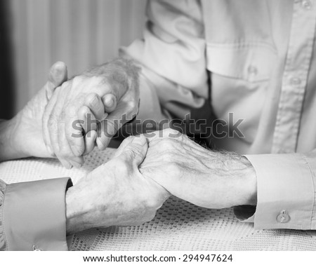Elderly man and woman. Elderly couple holding hands. Senior man, woman with their caregiver at home. Concept of health care for elderly old people, disabled. Black and white photo.