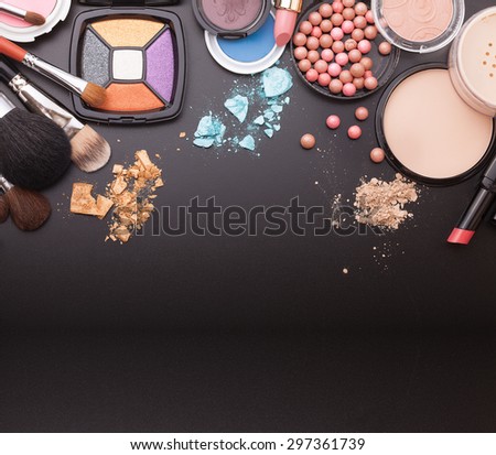 Various makeup products on black background with copyspace