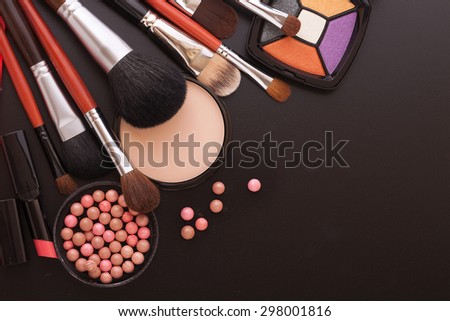 Colorful frame with various makeup products on black texture background. An unusual view, top view, mock up for design. Selective focus.