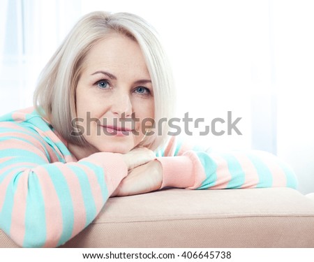Active beautiful middle-aged woman smiling friendly and looking into the camera at home. Woman\'s face close up.