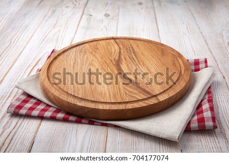 Napkin and board for pizza on wooden desk. Stack of colorful dish towels on white wooden table background top view mock up. Selective focus.