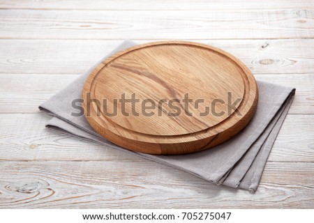 Napkin and board for pizza on wooden desk. Stack of colorful dish towels on white wooden table background top view mock up. Selective focus.