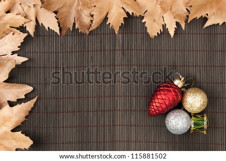 Frame of sycamore leaves and Christmas ornaments on bamboo background