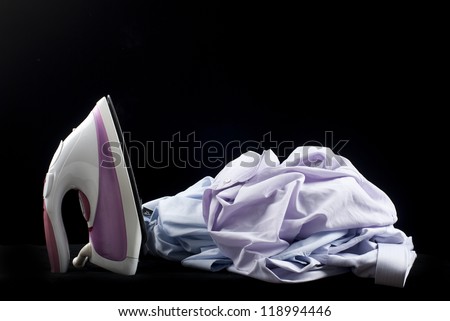 Hot steam iron with a pile of wrinkled clothing