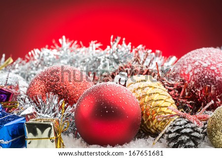 christmas accessories, gift boxes and spheres on snow on red background