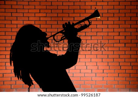 Man playing trumpet in front of a red brick wall