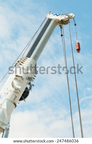 truck crane boom with hooks and scale weight above blue sky