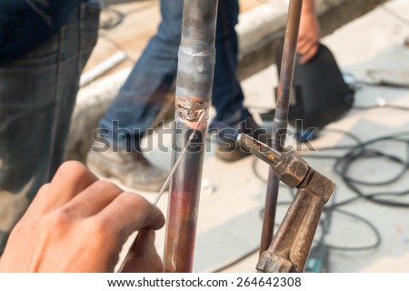 Plumbing contractor works sweating the joints on the copper pipe domestic water system on a luxury custom home