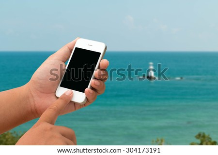 Mobile men and touchscreen smartphone, tablet, mobile phone over blurred beautiful clear blue sky and beach background. Abstract background for online work on the holiday.
