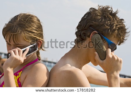 The girl talks by a mobile phone, the guy speaks on the phone from a stone