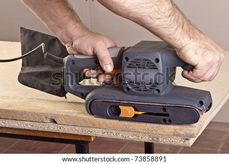 A man working with electrical sanding machine, close up on tool, hands and sparks, real situation picture