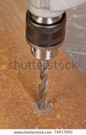 A man drilling a hole in the metallic sheet