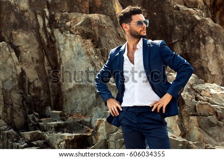 Man in elegant suite posing in rock background