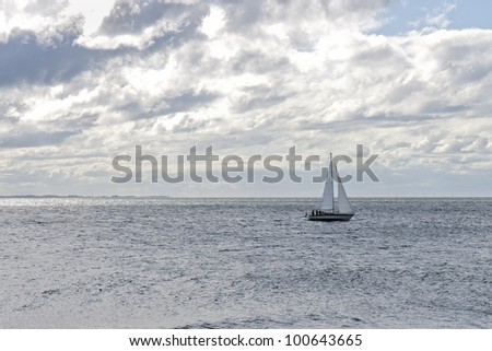 Clouds over the ocean with sailboat passing. Copy space