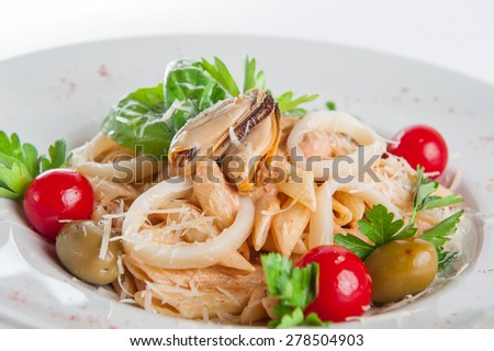 Close up  Plate of Seafood Pasta with squid, mussels with cream, decorated with cherry tomatos, olives, parmesan and herbs on the white plate isolated