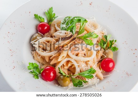 Close up  Plate of Seafood Pasta with squid, mussels with cream, decorated with cherry tomatos, olives, parmesan and herbs on the white plate isolated