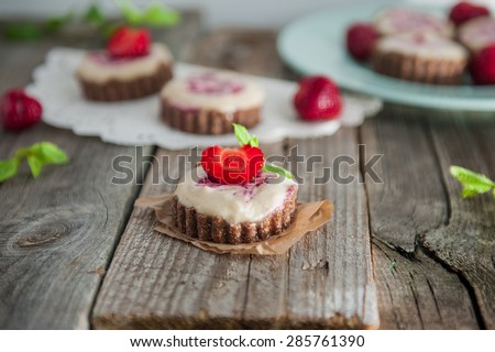 Home made Gluten and sugar free Delicious pies with whipped almond cream and strawberry jam, decorated with mint and fresh strawberries on a kitchen dark wooden table