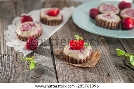 Home made Gluten and sugar free Delicious pies with whipped almond cream and strawberry jam, decorated with mint and fresh strawberries on a kitchen dark wooden table