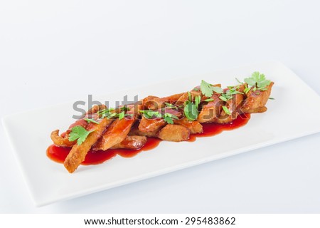 Traditional Japanese dish - chicken tempura with spicy sauce decorated by parsley and chives on a white plate isolated