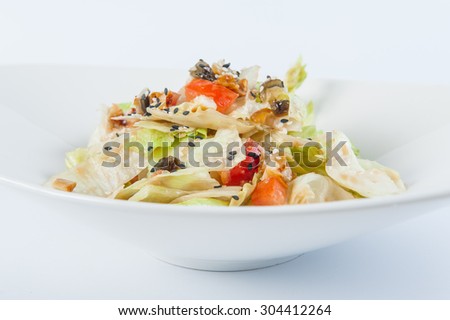 Close up Delisious diet salad with Chinese cabbage, seafood, lettuce, tomatoes, black sesame and soy sauce in a white plate isolated