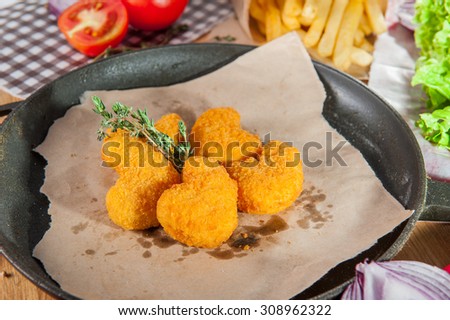 Traditional american fast food - chicken nuggets in the pan on the table  arounded some ingredients