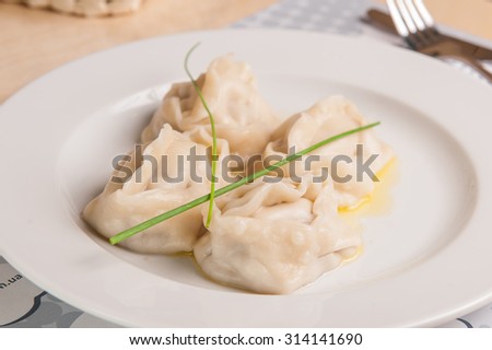 Close up tasty traditional asian steam dumplings with meat filling on a white plate on the serverd restaurant table