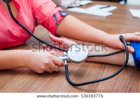 Close up view of female medicine doctor measuring blood pressure to her patient. Hands close up. Healthcare, healthy lifestyle and medical service concept