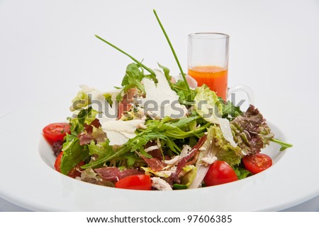 Close up Italian Salad mix with chicken breast, bacon, tomatoes cherry, arugula, lettuce and sliced parmesan served with carrot sauce in the round white plate isolated on the white background
