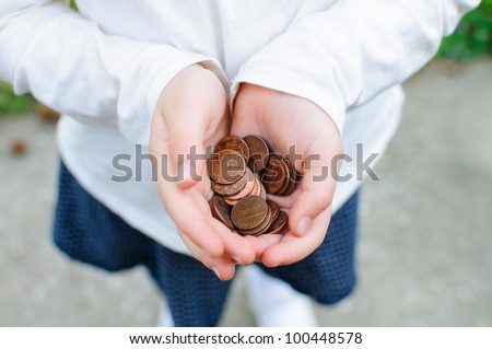 A handful of pennies rest in a girl's cupped hands.