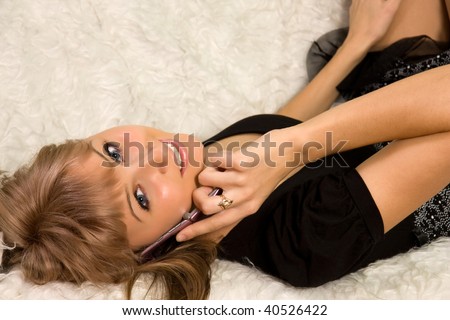 The young beautiful woman lays on a sofa and talks by mobile phone