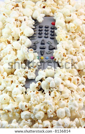 television remote control under  pop corn background food and entertainment concepts