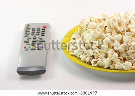 yellow paper plate with pop corn and television remote control food and entertainment concepts
