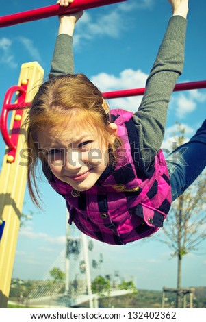 A child goes in for sports on a horizontal bar outside