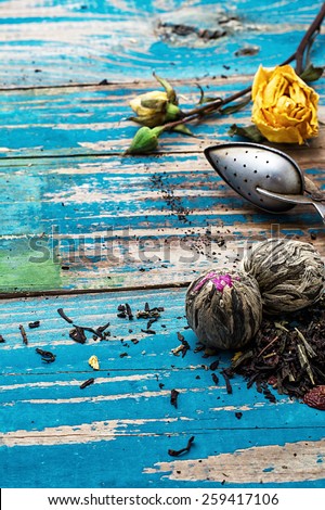 Tea leaves for brewing,tea spoon and dried yellow rose.The image is tinted in vintage style