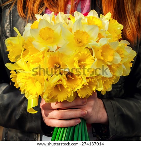 silhouette of girl with red hair with bouquet of daffodils hands.Selective focus