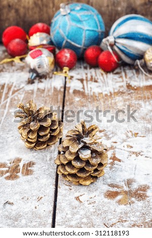 Two pine cones on the background of snow-covered Christmas ornaments