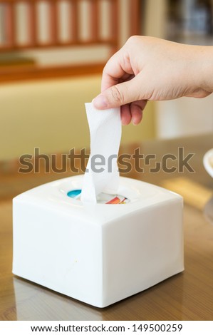 Woman\'s hand pulling a tissue from a white tissue box