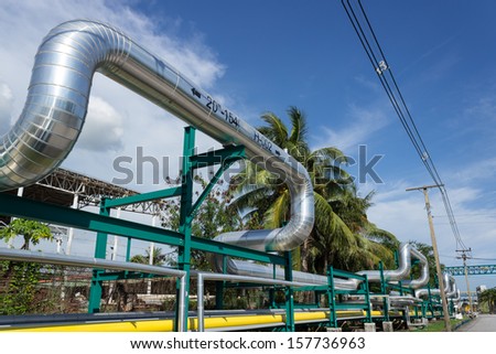 Industrial pipelines on pipe bridge against blue sky in Thailand.