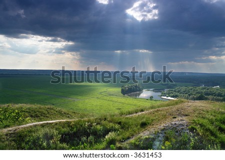 countryside in back lighting. Storm clouds and sun rays