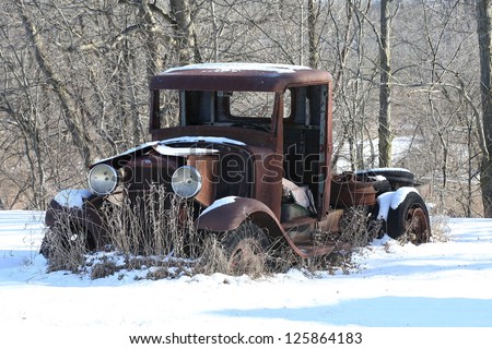 Old rusted pick-up truck covered in snow
