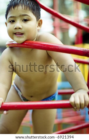 kid playing inside red bars structure in the playground
