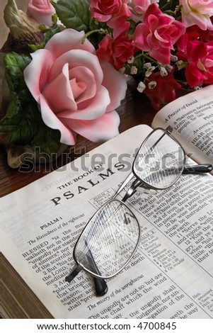 An open Bible turned to Psalms on a table with reading glasses.
